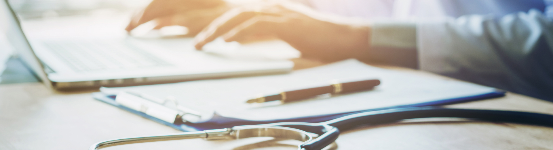 Doctor typing information on Laptop in Hospital office focus on Stethoscope