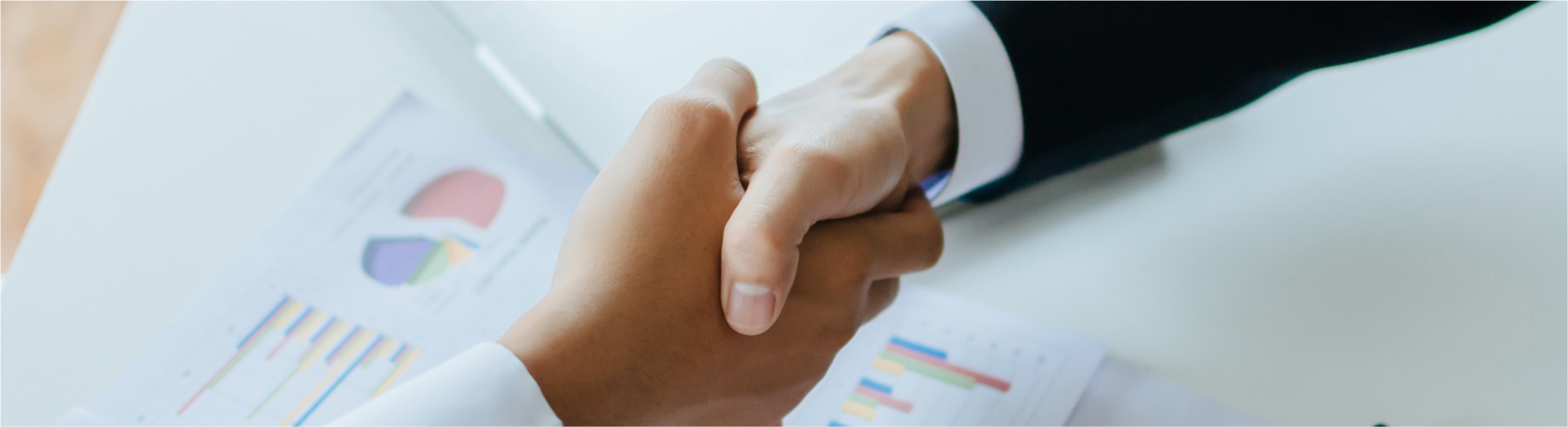 Partnership. two business investor people partner handshake after finishing up business meeting with financial statistics report on desk in office