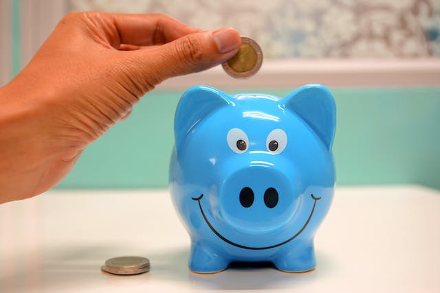 person dropping coin in blue piggy bank