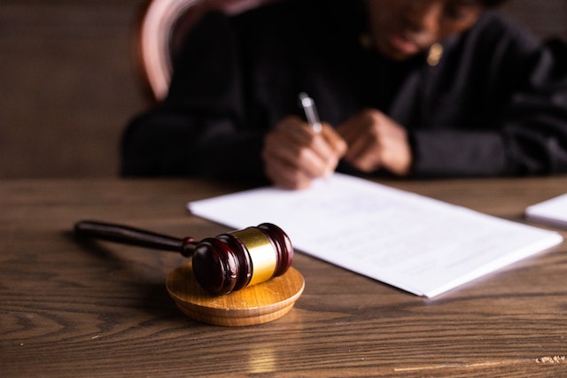 judge signing paperwork with gavel on table